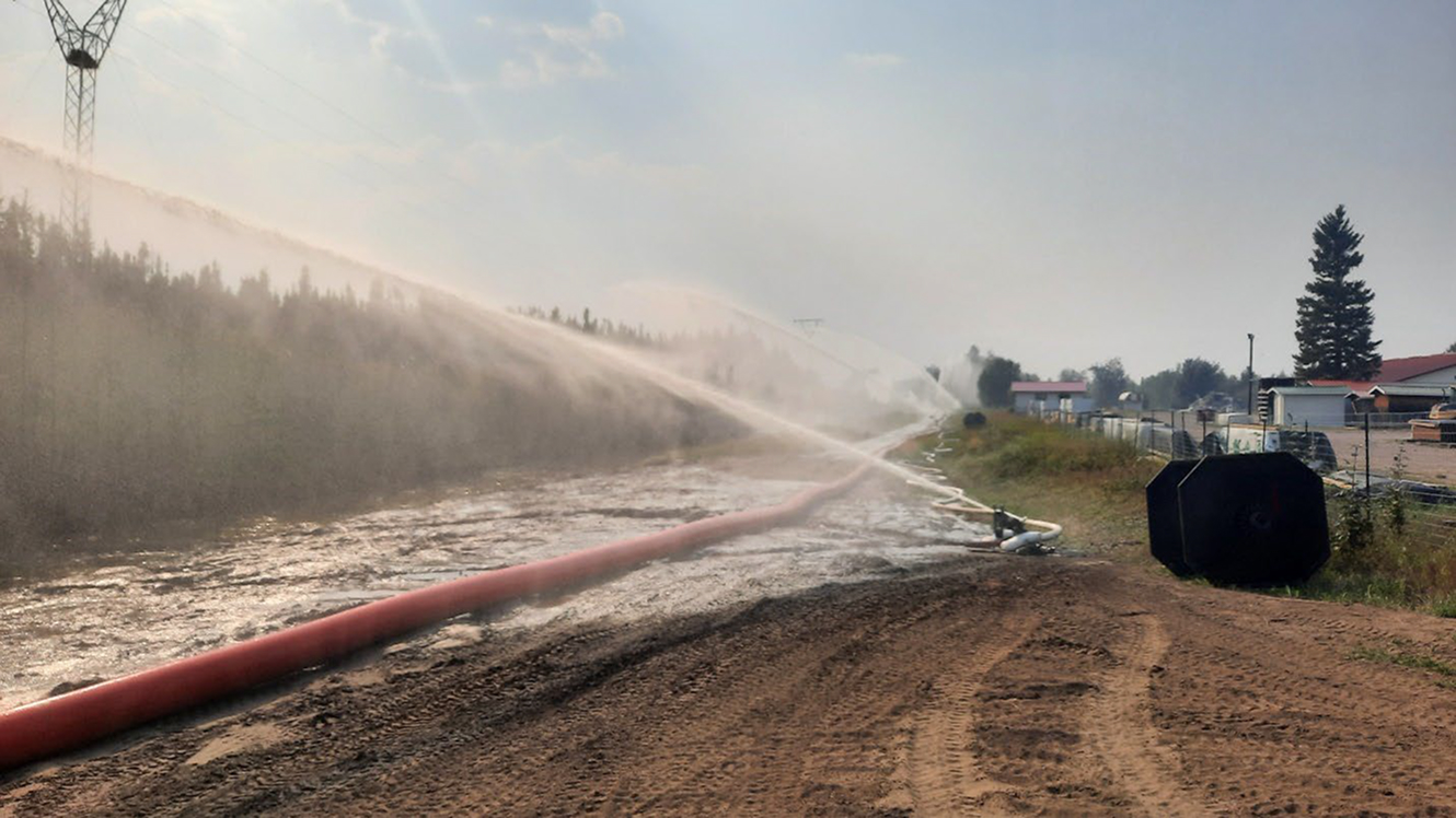 Water spray from hose over dirt road construction site