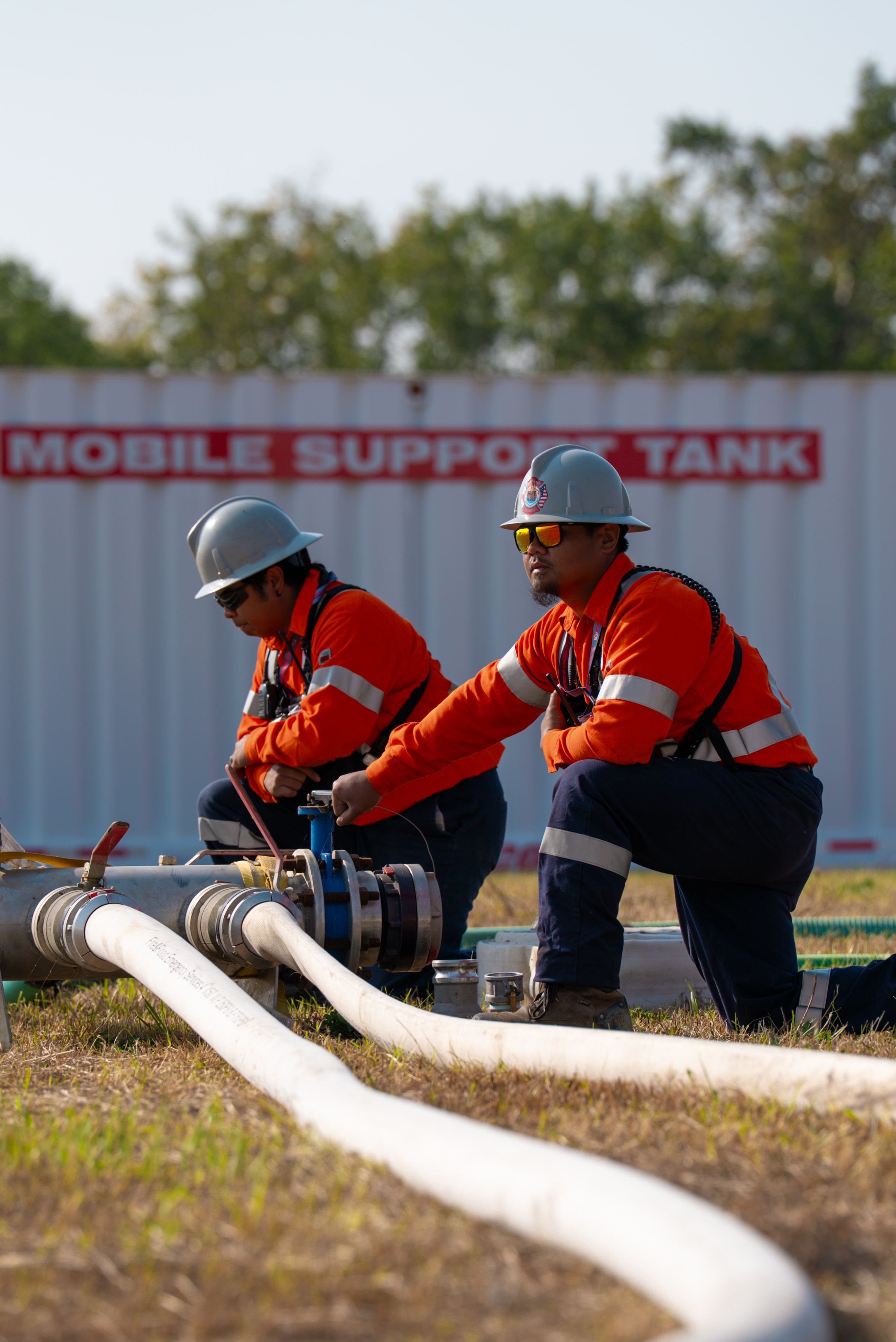 Two men dressed in red using an equipment outdoors