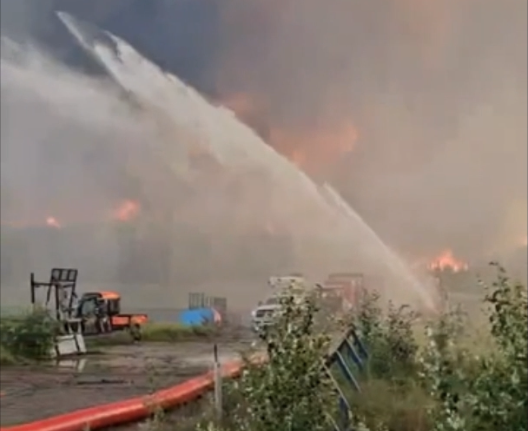 Firefighters spraying water on large industrial fire